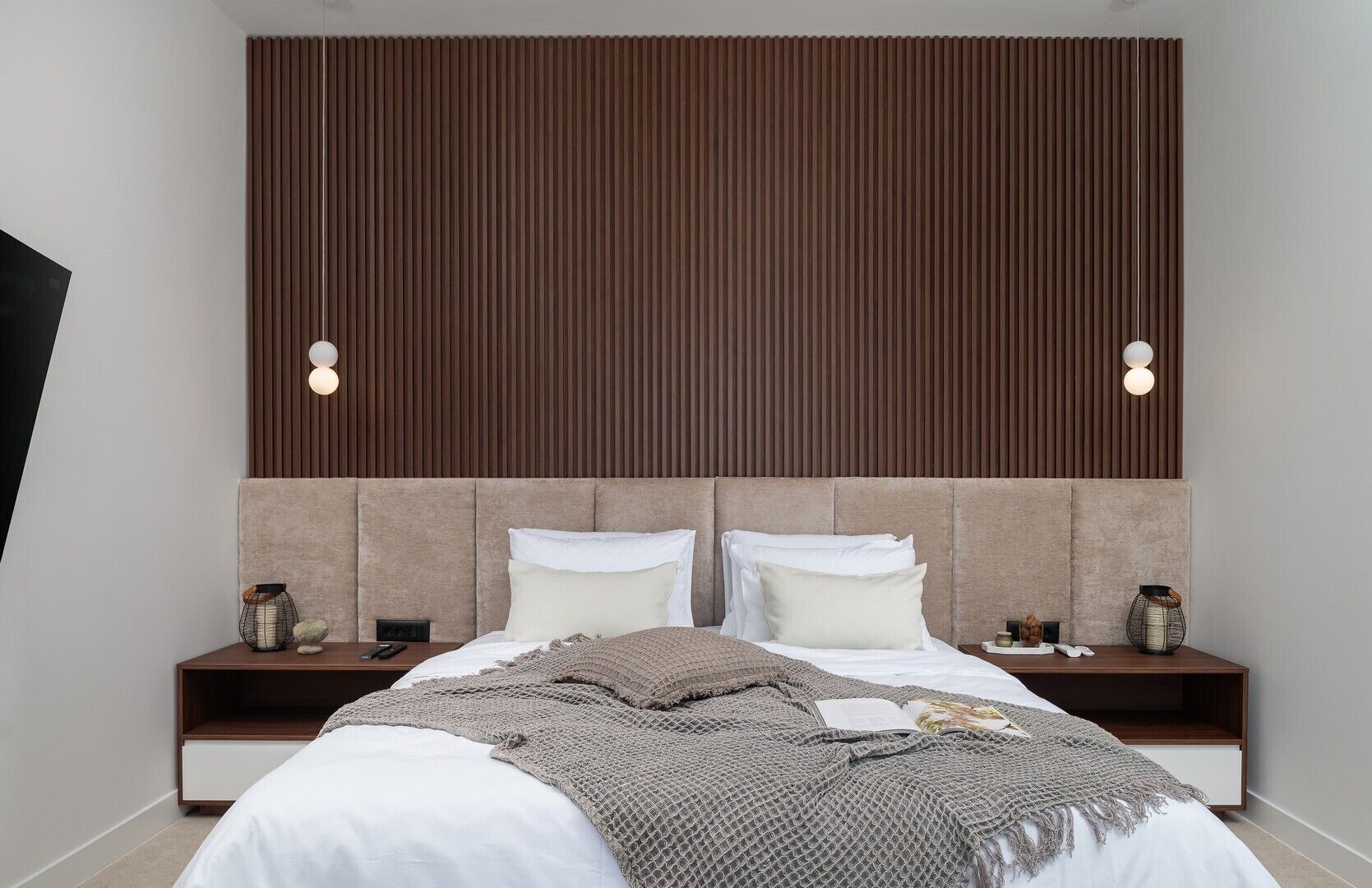 Ein modernes Schlafzimmer mit einem großen Bett, zwei Nachttischen und einer Wandleuchte.