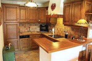 A kitchen with wooden cabinets, a microwave, a stove, and a sink.