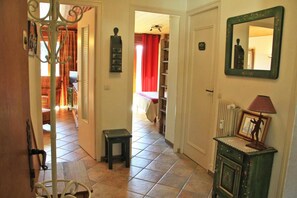 A hallway with a tiled floor, a small stool, a mirror, and a radiator.