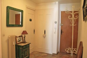 A hallway with a radiator, a framed photo, a lamp, a door, and a coat rack.