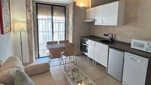 Cocina compacta con comedor, sofá y ventana con cortinas.