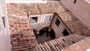Un patio con tejado de baldosas, pared de ladrillo y un pequeño arco.
