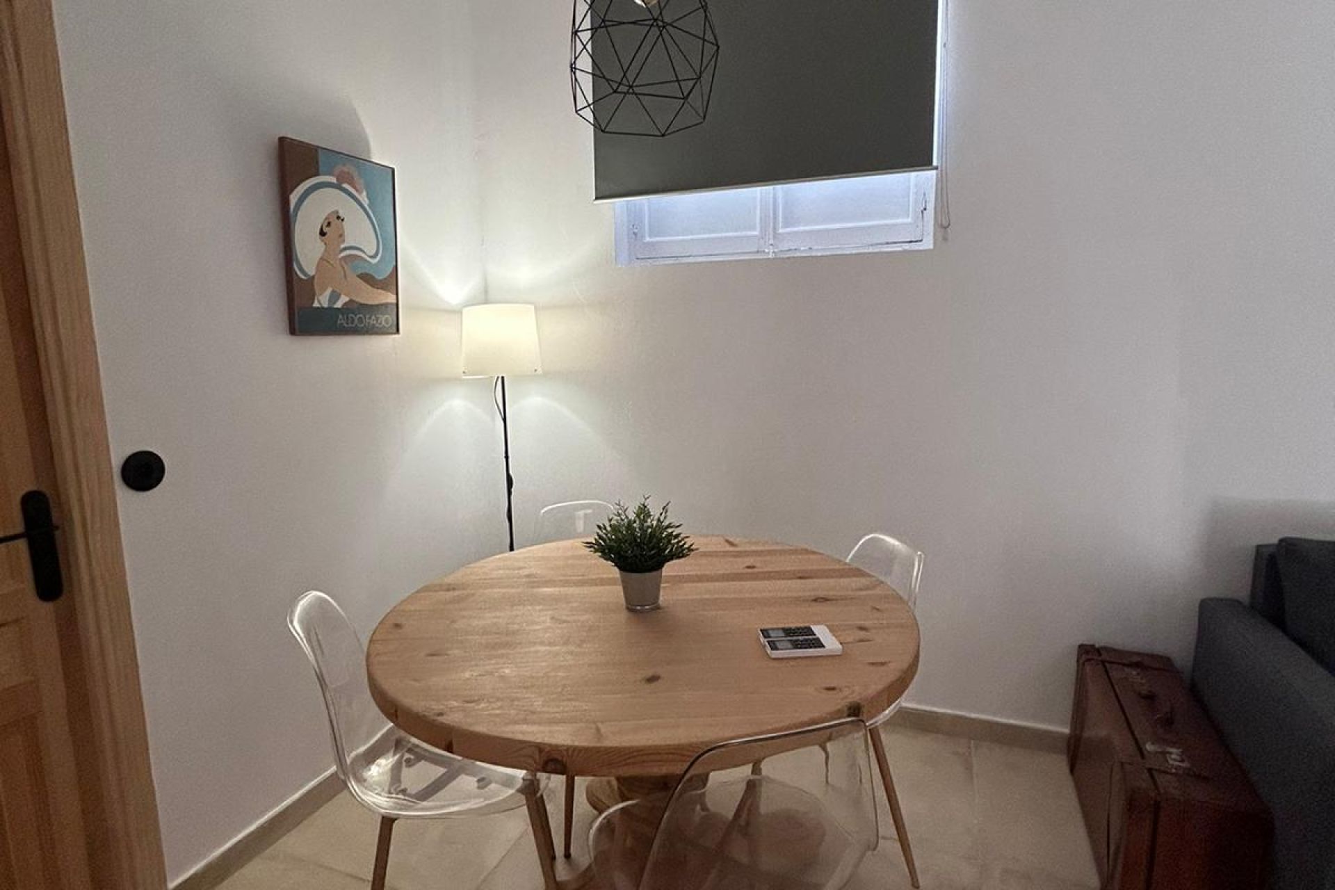 Ett litet runt bord i trä med fyra stolar, en krukväxt och en lampa.