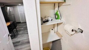 Una cocina compacta con refrigerador, una pequeña mesa de comedor y una puerta blanca que da a otra habitación.