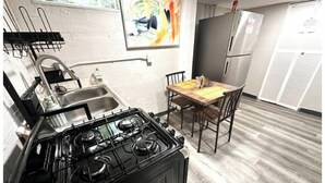 Una cocina con estufa, fregadero y mesa de comedor.