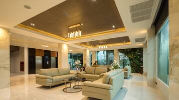 A spacious lobby with a sectional sofa, a coffee table, and a large window offering a view of greenery.