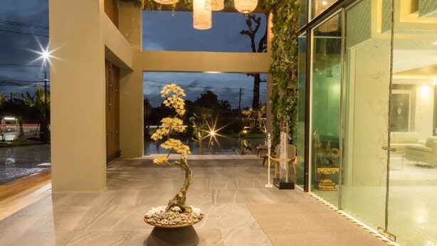 A modern building with a glass facade, a central staircase, and a bonsai tree. - Benjaphorn Grandview Hotel (Songkhla)