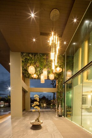 A modern building with a glass facade, a central staircase, and a bonsai tree. - Benjaphorn Grandview Hotel (Songkhla)