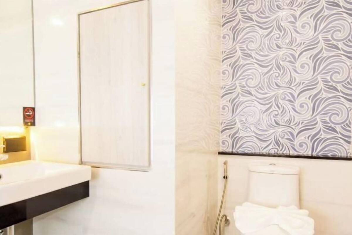 A bathroom with a white sink, a towel, and a patterned wall.