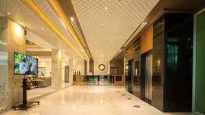 A spacious lobby with a high ceiling, a reception desk, and a television screen. - Benjaphorn Grandview Hotel (Songkhla)