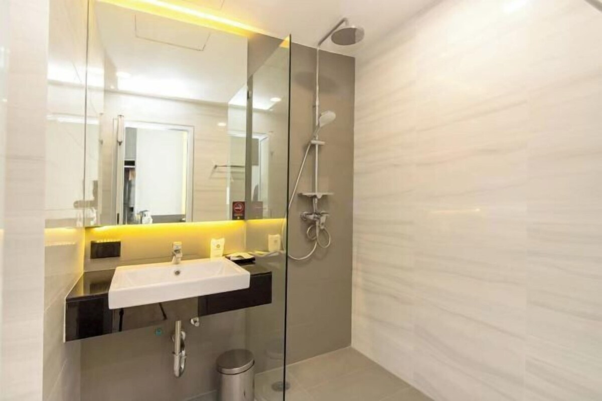 A modern bathroom with a glass-enclosed shower, a white sink, and a mirror.