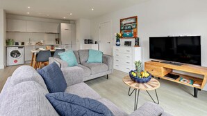 Ett modernt vardagsrum med en grå soffa, ett TV-bord och en matplats med ett bord och stolar.
