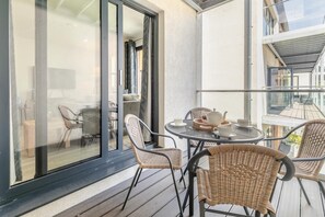 A balcony with wicker chairs, a table, and a tea set.