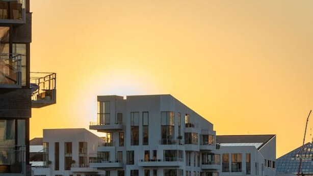 A modern multi-story residential building with balconies, located near a body of water with boats docked. - Scandinavian Premium Atelier - Spacious Comfort (København)