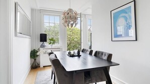 Un comedor con una mesa de madera oscura, sillas tapizadas en gris, una lámpara colgante y un cuadro en la pared.