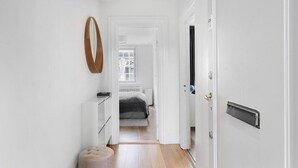Un pasillo estrecho que conduce a un dormitorio con cama, cómoda y espejo en la pared.