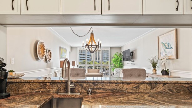 A modern kitchen with granite countertops, a stainless steel sink, and a chandelier. - Kingston South Hampton 203 - 2 BD Oceanview Condo (North Myrtle Beach)