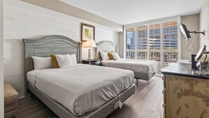 A hotel room with two beds, a bedside table with a lamp, a dresser, and a large window with blinds. - Kingston South Hampton 203 - 2 BD Oceanview Condo (North Myrtle Beach)