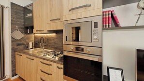A modern kitchen with wooden cabinets, a stainless steel range, and a built-in oven. - Modern Apartment in Rome 200 meters from Metro Line A


 (Roma)