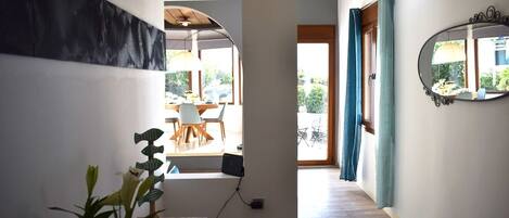Un pasillo con suelo de madera, un comedor con sillas y una mesa, y un espejo grande en la pared.