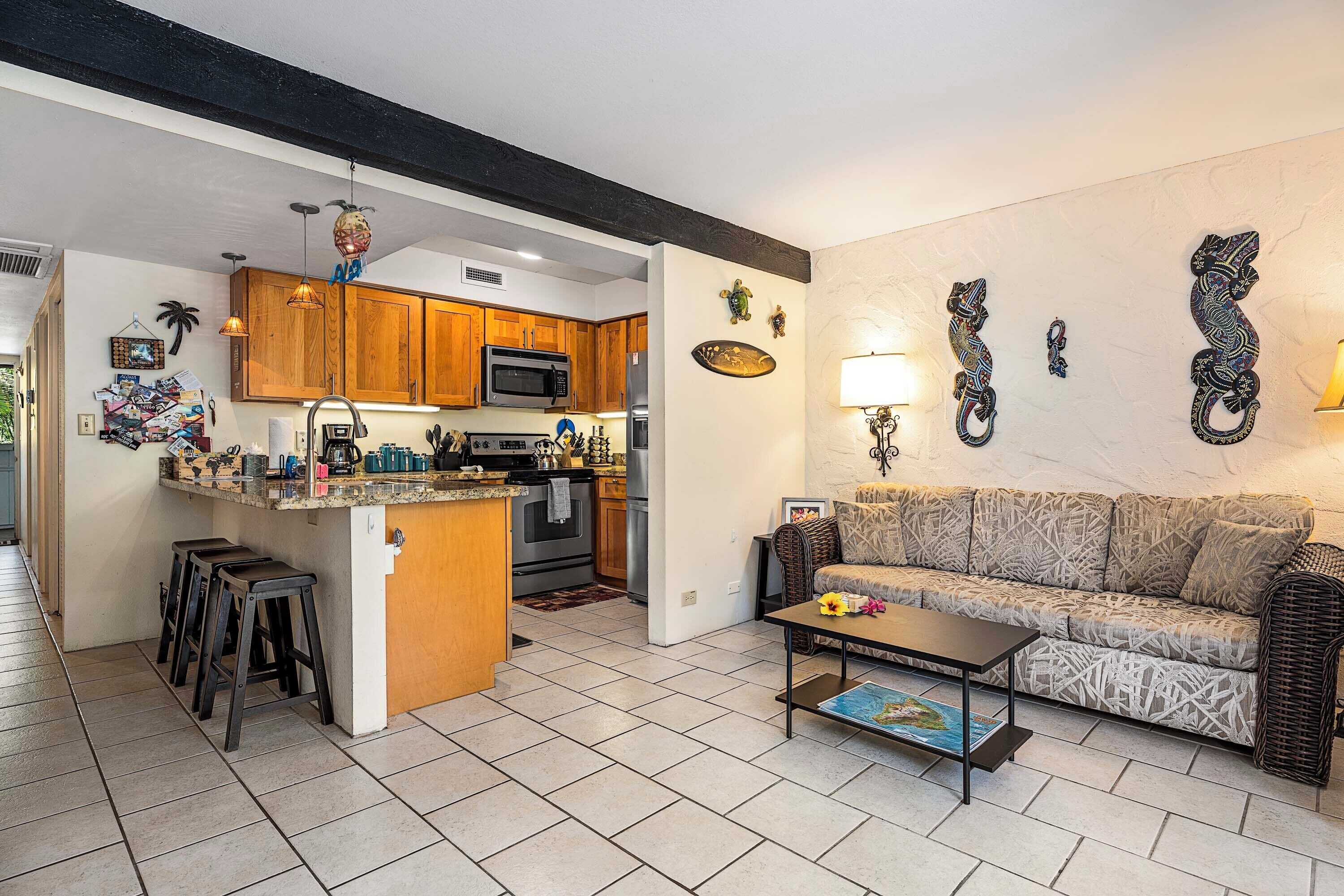 A modern kitchen with wooden cabinets, a central island, and a dining area with a sofa and coffee table.