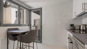 A modern kitchen with a dining area, featuring a table and chairs, a stove, and cabinets. - Holiday Home with Pool by Costarentals - Ref 251 (Las Lagunas de Mijas)