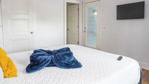 A bedroom with a bed, a blue blanket, a yellow pillow, a TV on the wall, and two doors. - Cozy and Gorgeous 2br/1ba Near Amazing Downtown (San Antonio)