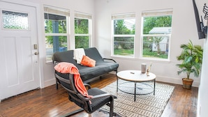 A room with a black sofa, a chair, a small round table, and a potted plant. - Cozy and Gorgeous 2br/1ba Near Amazing Downtown (San Antonio)