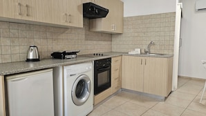 A compact kitchen with a washing machine, a stove, and a microwave. - Phaedrus Living: Hoopoe Residencies 105 (Nicosia)