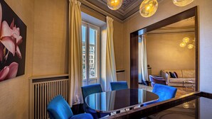 A modern hotel room with a round table, blue chairs, a large mirror, and a view of the city through the window. - YID SMN LUX (Florence)