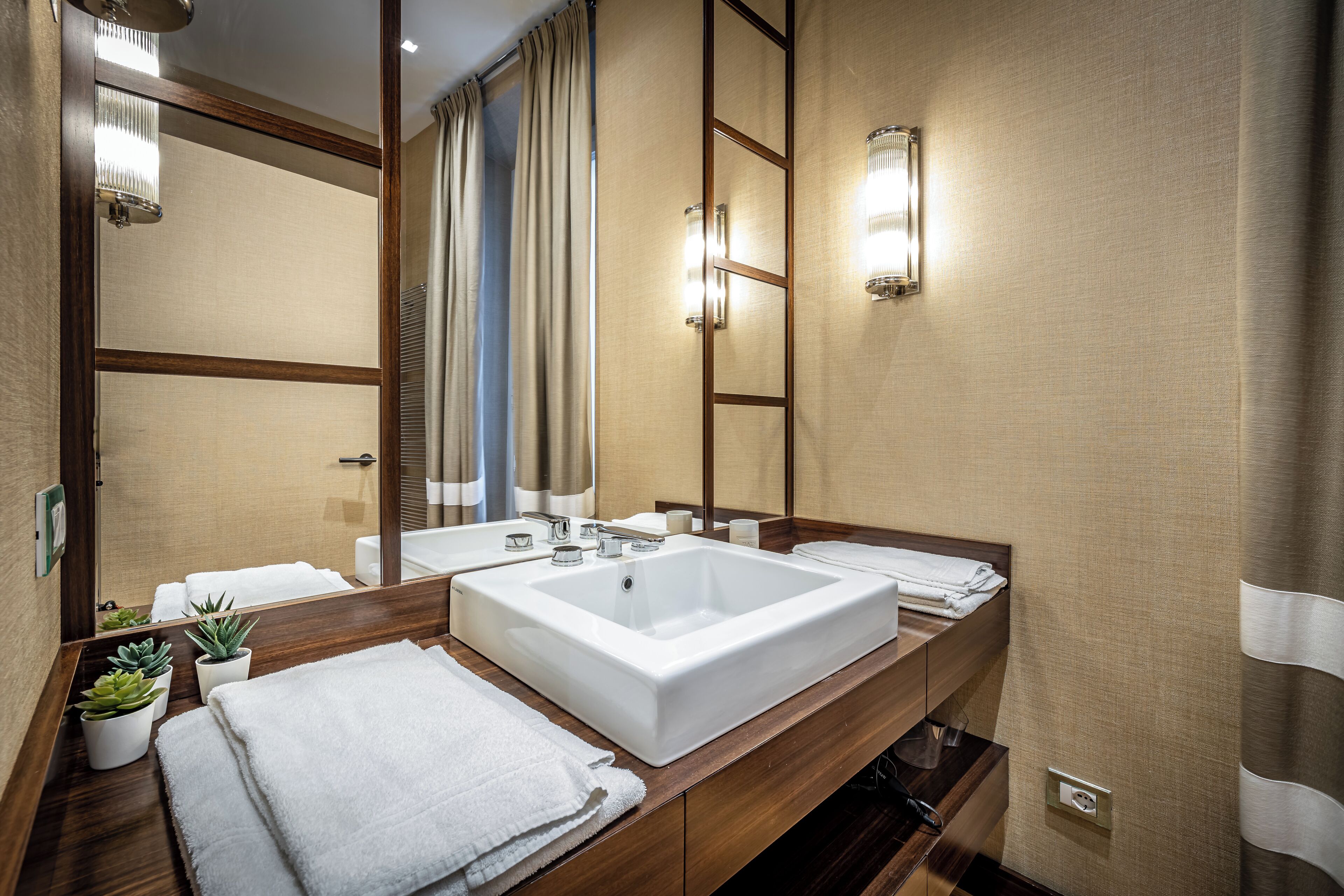 A modern bathroom with two sinks, a large mirror, and a wooden vanity.