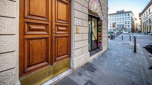 A hotel entrance with a large wooden double door, a signboard above the door, and a tiled sidewalk. - YID SMN LUX (Florence)