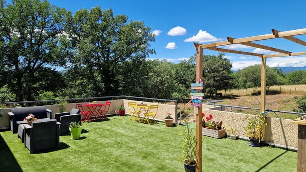 Eine Terrasse mit Gartenmöbeln, einer Pergola und einem Wegweiser mit verschiedenen Zielortnamen.