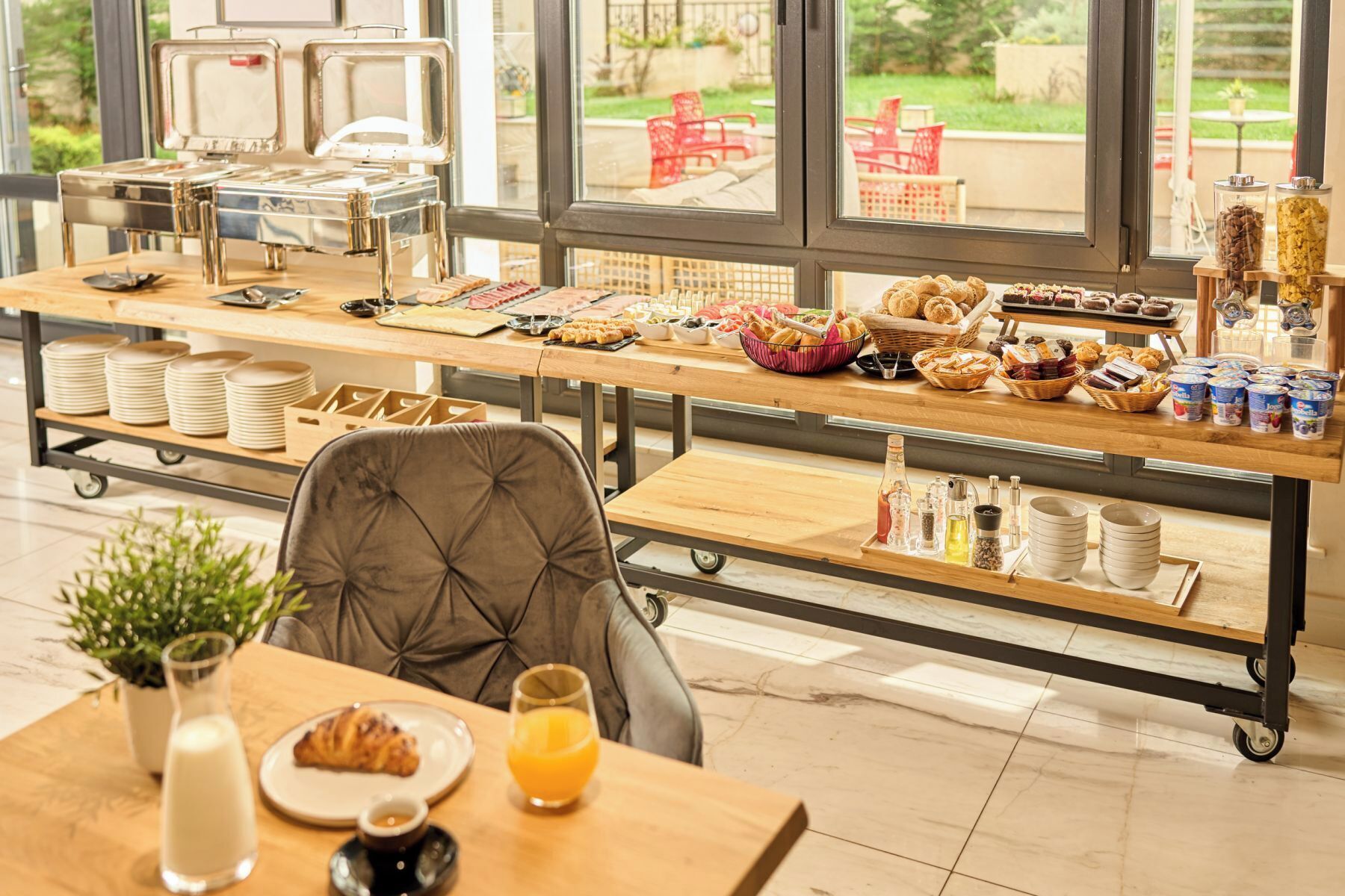 Un buffet de petit-déjeuner proposant une variété d’aliments, un coin café et une vue sur l’extérieur.