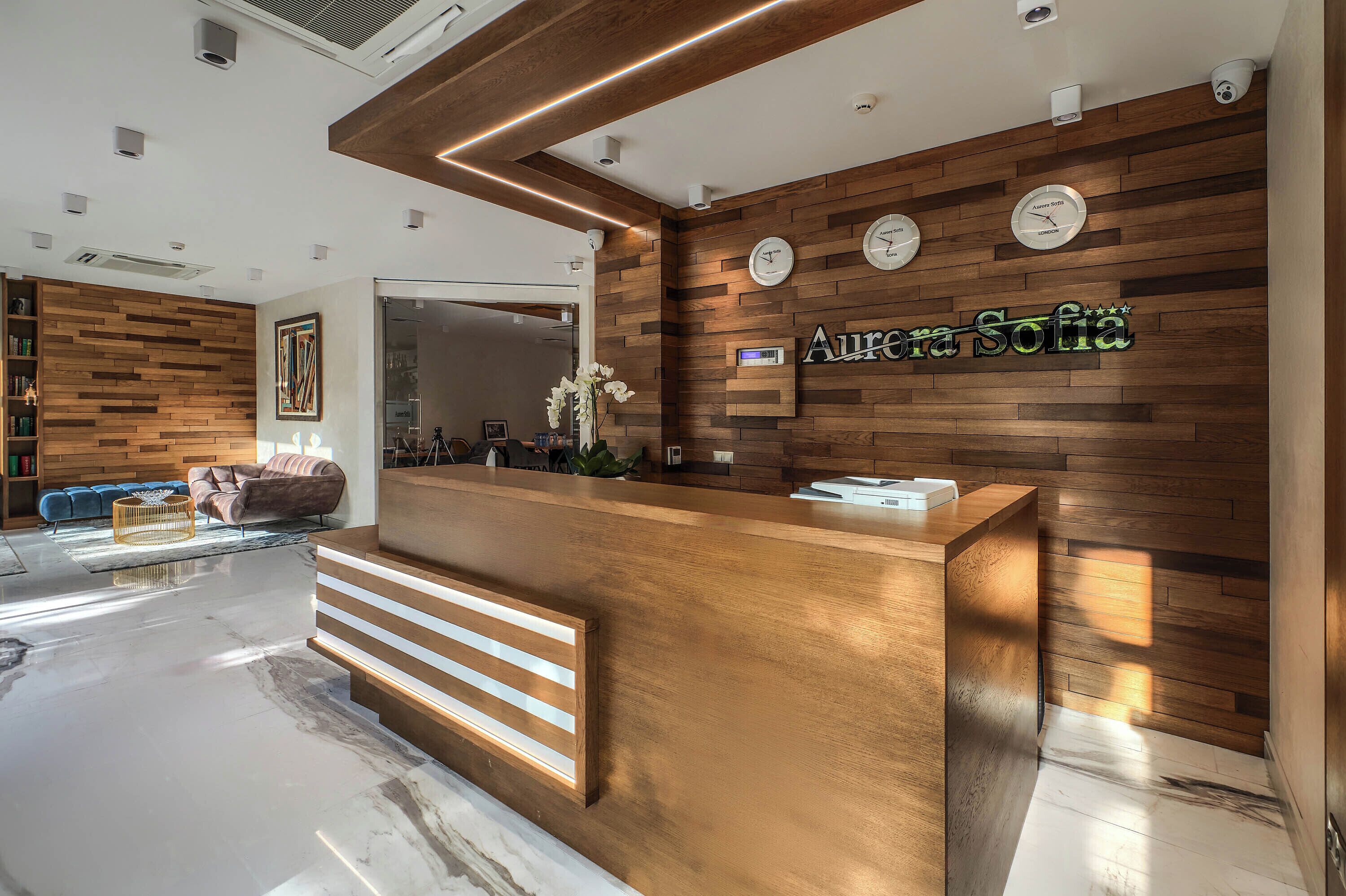 A reception desk with a wooden finish, a clock, and the name 'Aurora Sofia' on the wall.