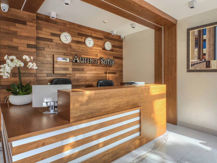 Una recepción con detalles de madera, un reloj y una pantalla digital.