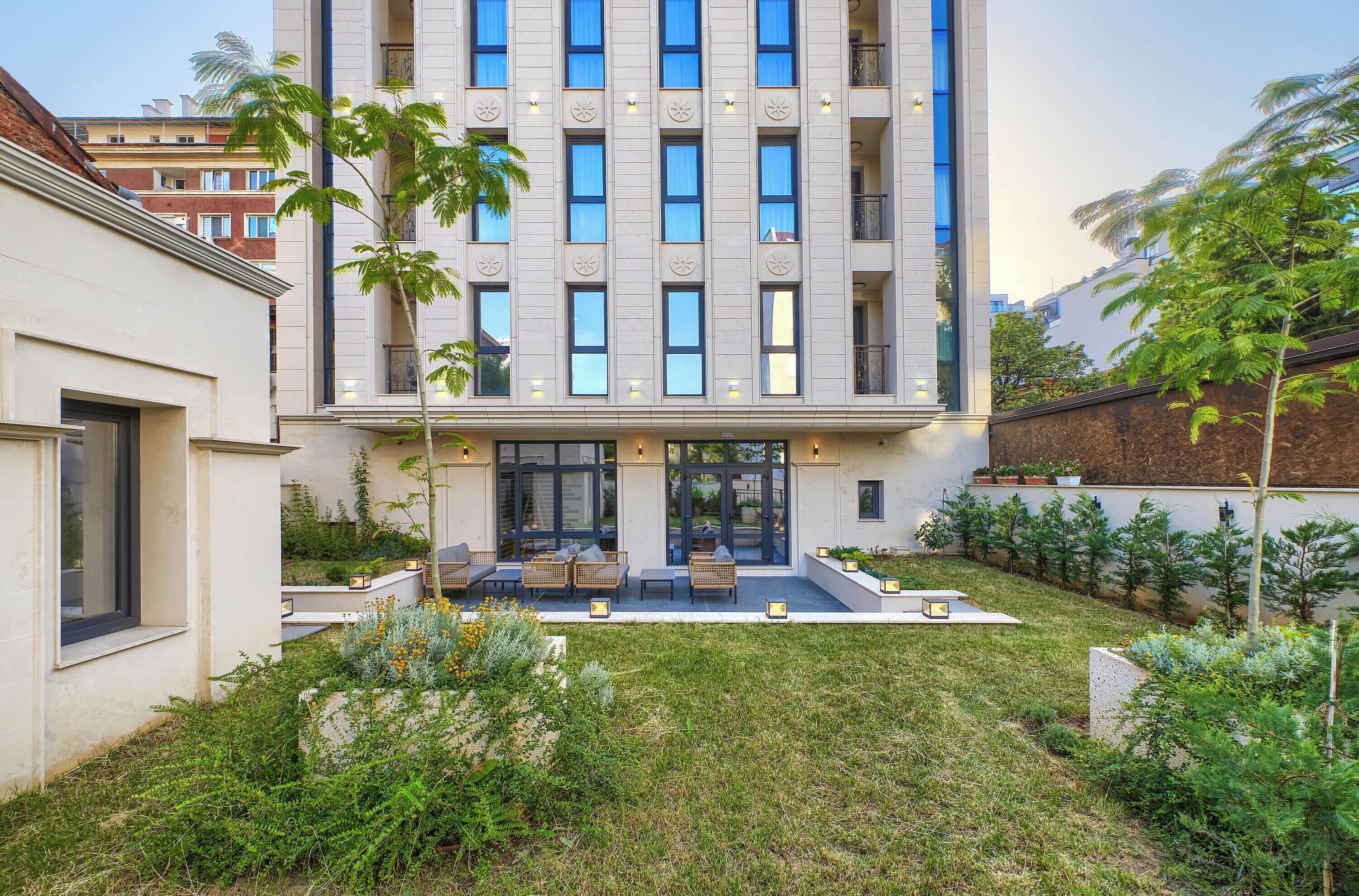 A modern building with a courtyard featuring outdoor seating and greenery.