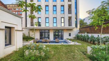 A modern building with a courtyard featuring outdoor seating and greenery.