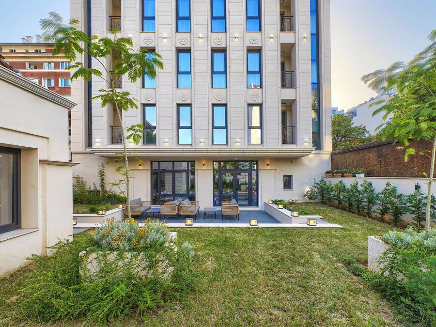 A modern building with a courtyard featuring outdoor seating and greenery.
