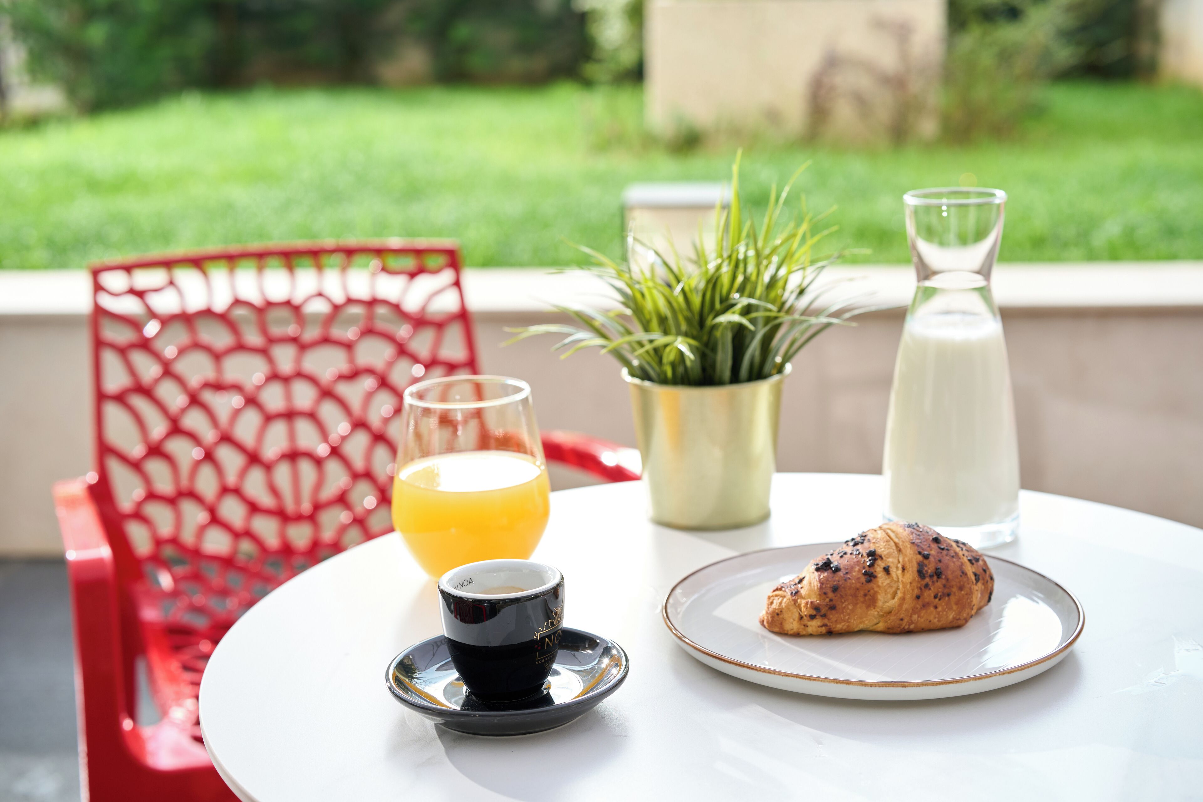 A table with a croissant, a glass of orange juice, a coffee cup, and a bottle of milk.