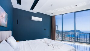Moderni hotellihuone, jossa on suuri sänky, merinäköala ja taulu seinällä.