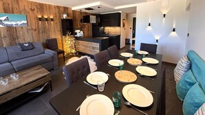 Un salon moderne avec un coin repas, des murs en bois et une cuisine à l’arrière-plan.