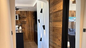 Un couloir moderne avec un mur d’accent en bois, un coin cuisine doté d’un four encastré et un espace salon offrant une vue sur l’extérieur.