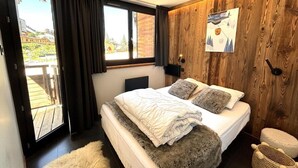 Une chambre à coucher avec un lit, une fenêtre, un mur en bois et une vue sur l’extérieur.