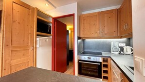 Una cocina compacta con armarios de madera, horno integrado y cafetera.