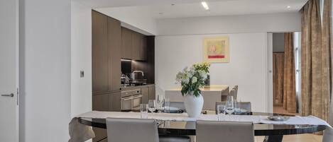 Un espace repas moderne avec une longue table, des chaises et un vase de fleurs.