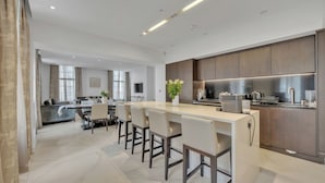 A modern kitchen with a central island, bar stools, and built-in appliances.