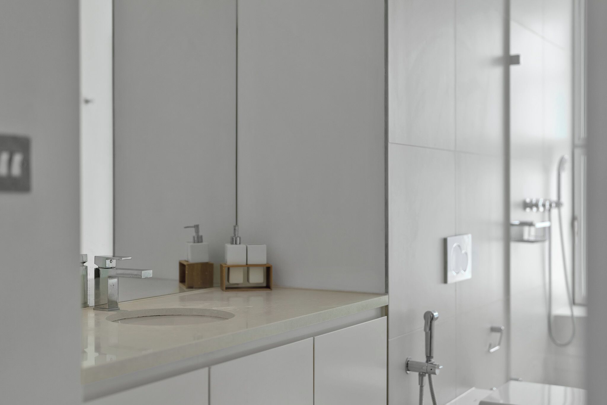 Un baño moderno con un espejo grande, un lavamanos y una zona de ducha.