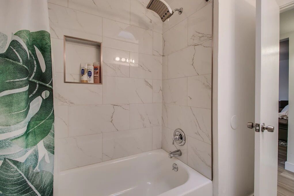 Une salle de bain équipée d’une baignoire, d’une douche et d’une étagère où sont rangés les articles de toilette.