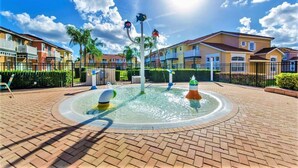 Zona residencial con fuente central, casas con balcones y cielo despejado.